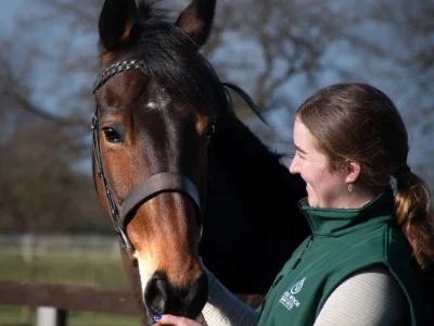 A vet standing next to a horse in a medium close up.